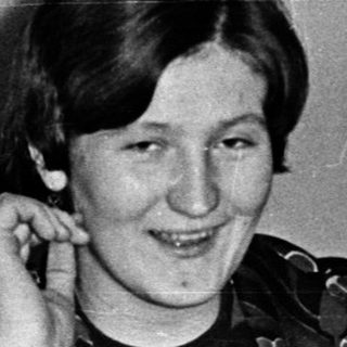 Woman smiling at table during indoor gathering.
