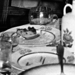 Woman smiling at table during indoor gathering.