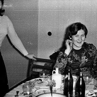 Woman smiling at table during indoor gathering.