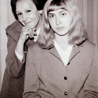 Two women posing together in vintage attire.