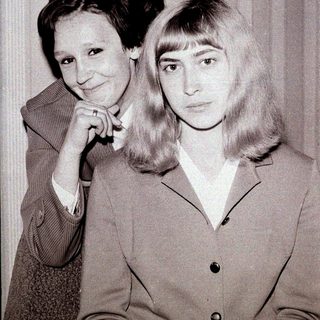 Two women posing together in vintage attire.