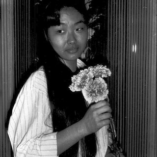 Woman in traditional attire holding flowers indoors.