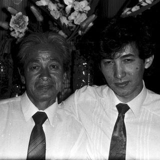 Two men posing indoors, one older, one younger.