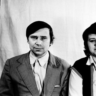 Two individuals in formal attire, posing together.