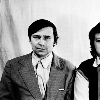 Two individuals in formal attire, posing together.