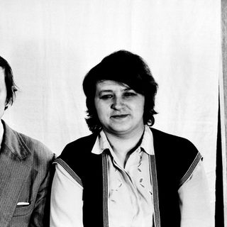 Two individuals in formal attire, posing together.