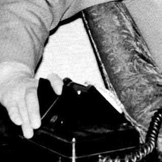 Man in 1970s-style suit seated indoors.