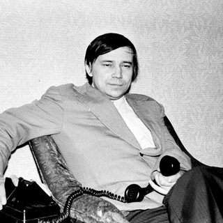 Man in 1970s-style suit seated indoors.
