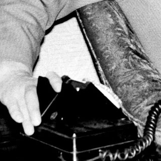 Man in vintage suit using rotary telephone.