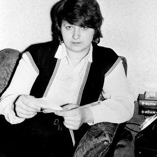 Young man reading newspaper in vintage vest.