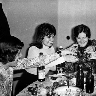 Group of people toasting indoors with wine.
