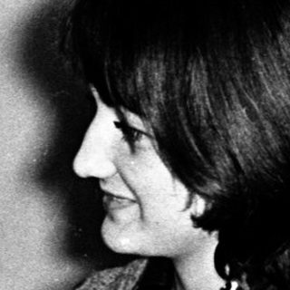 Two women at a table, one resting head, other smiling.