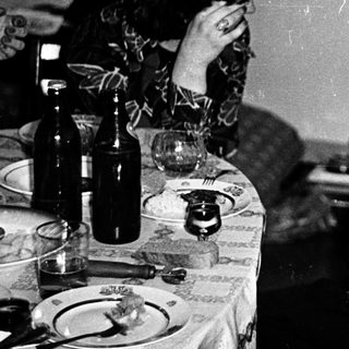 Two women at a table, one resting head, other smiling.