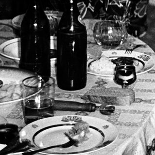 Two women at a table, one resting head, other smiling.