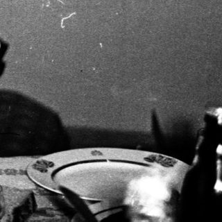 Woman seated at table with microphone, possibly speaking.