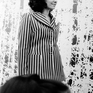 Woman in striped dress speaking at event.