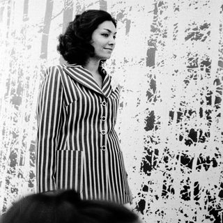 Woman in striped dress speaking at event.