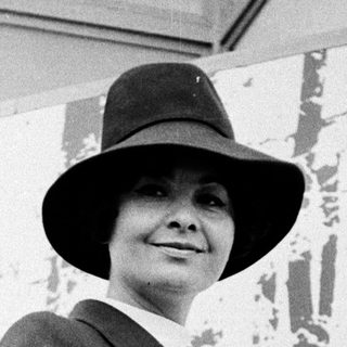 Elegant woman in 1950s-style suit and hat.