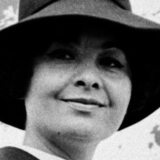 Elegant woman in 1950s-style suit and hat.
