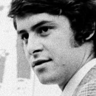 Young man in 1970s-style suit indoors.
