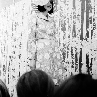 Elegant woman in floral dress poses indoors.