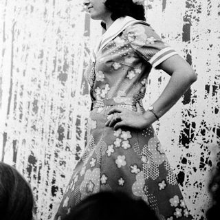 Woman in vintage nurse uniform with floral dress.