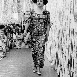 Model walks down runway in colorful patterned outfit.