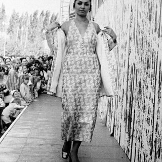 Fashion show model walking down runway.