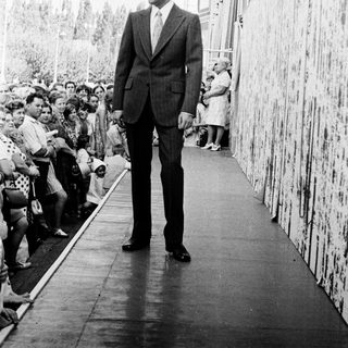Man in suit walking past cheering crowd.