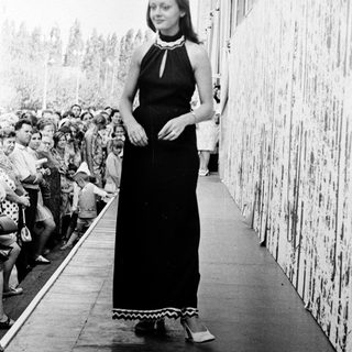 Elegant woman in long black dress on ship deck.