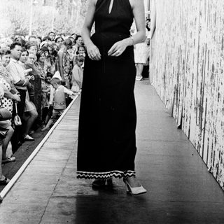Elegant woman in long black dress on ship deck.