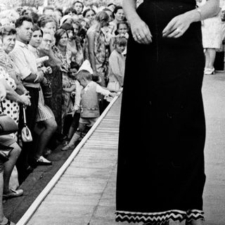 Elegant woman in long black dress on ship deck.