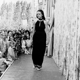 Woman walking alone in crowded outdoor corridor.