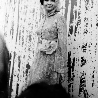 Young woman in elegant 1950s-style dress posing indoors.