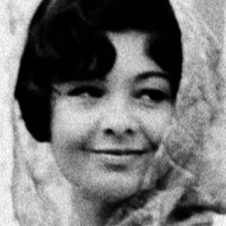 Young woman in elegant 1950s-style dress posing indoors.