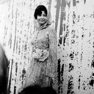 Young woman in elegant 1950s-style dress posing indoors.