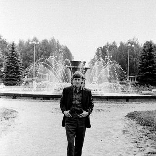Man in vintage attire posing near fountain.