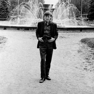 Man in vintage attire posing near fountain.