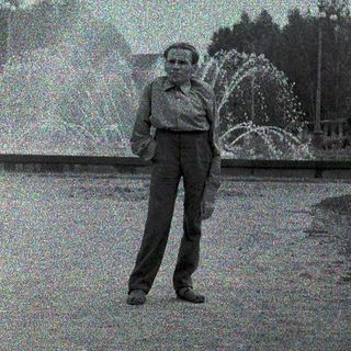 Man standing near water fountain in park.