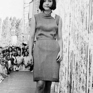 Fashion model walking on runway with audience.