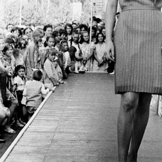 Fashion model walking on runway with audience.