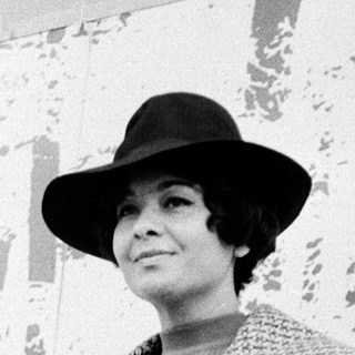 Elegant woman in 1950s-style coat and hat.