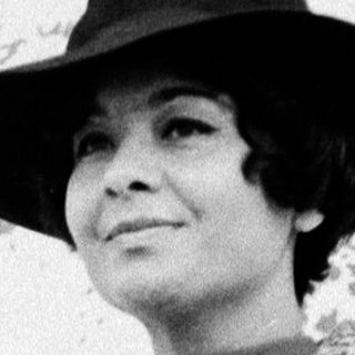Elegant woman in 1950s-style coat and hat.
