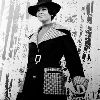 Elegant woman in 1950s-style coat and hat.