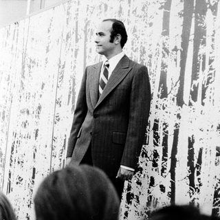 Man speaking at an art exhibition.