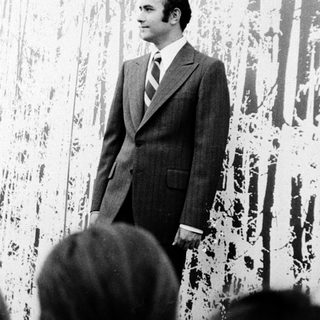 Man speaking at an art exhibition.