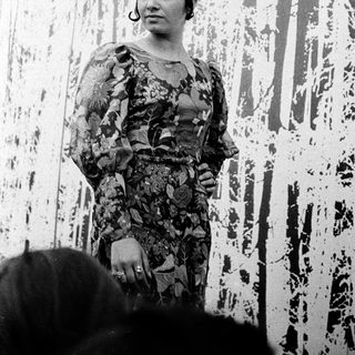 Woman in floral dress posing near abstract wall art.