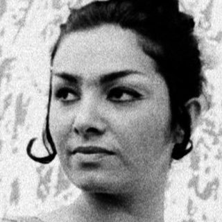 Woman in floral dress posing near abstract wall art.