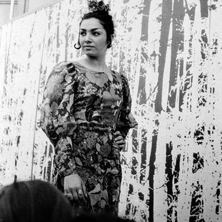Woman in floral dress posing near abstract wall art.