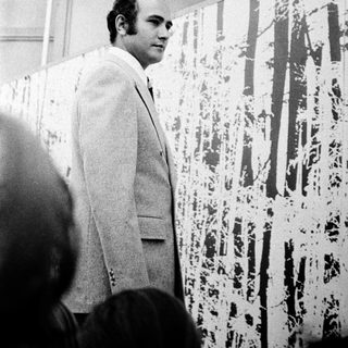 Man in suit examining abstract splatter art.